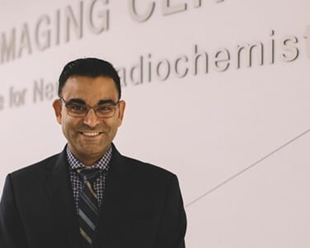 A man of colour standing in front of the Azrieli Centre for Neuro-Radiochemistry