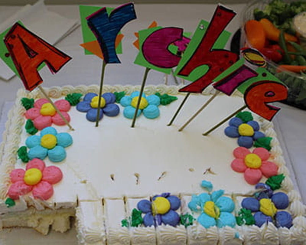 A frosted white cake that has Archie on it.