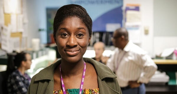 A female CAMH staff of colour wearing a forest green cardigan, posing for a picture in one of the nursing stations. 