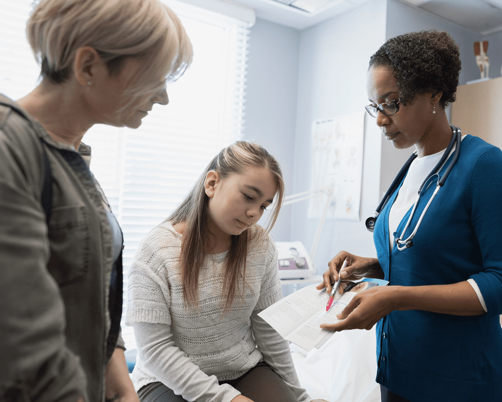 mother and daughter look at information pamphlet with medical professional