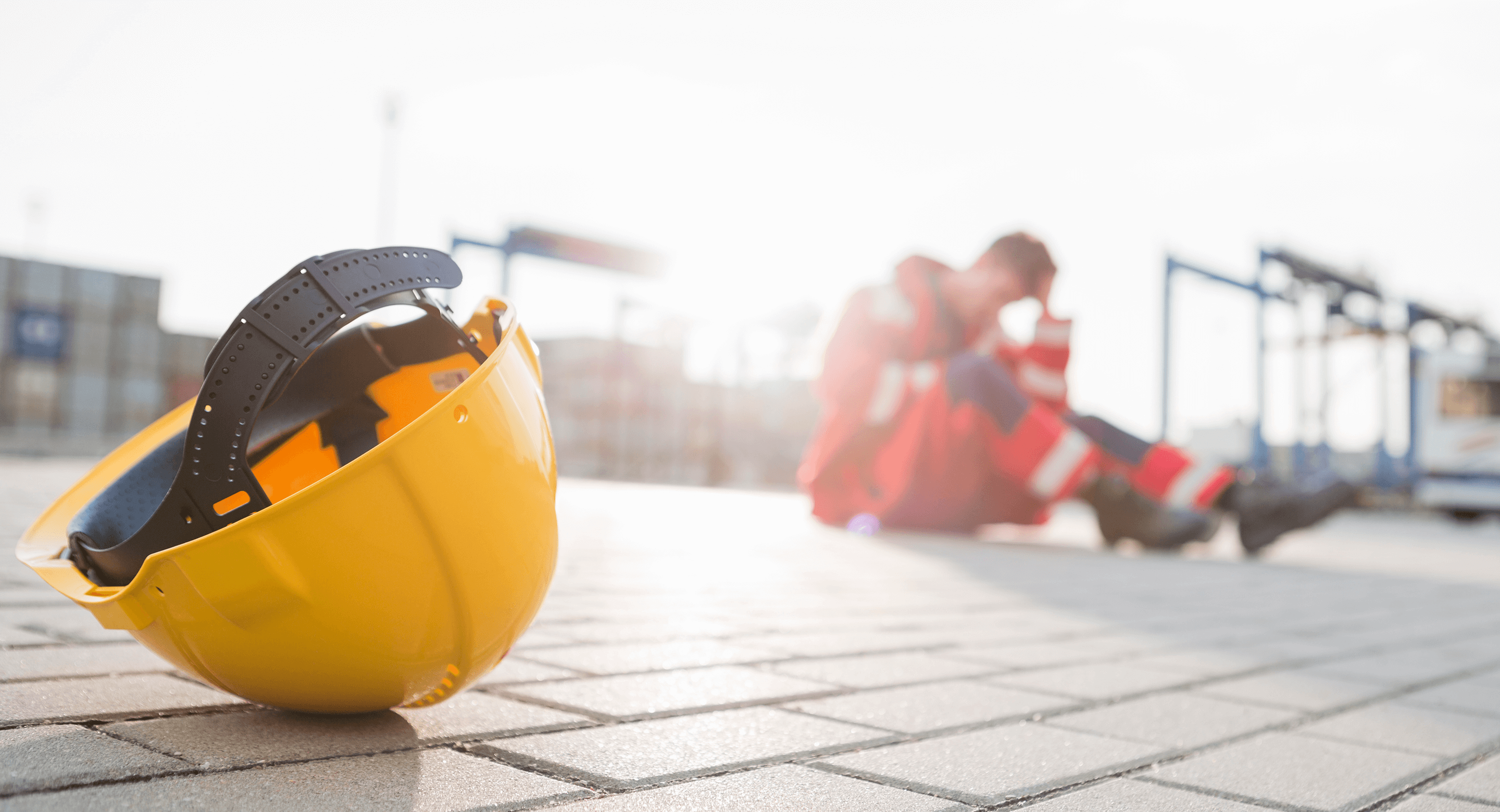 Construction worker sitting on ground, confused and worried after layoffs.