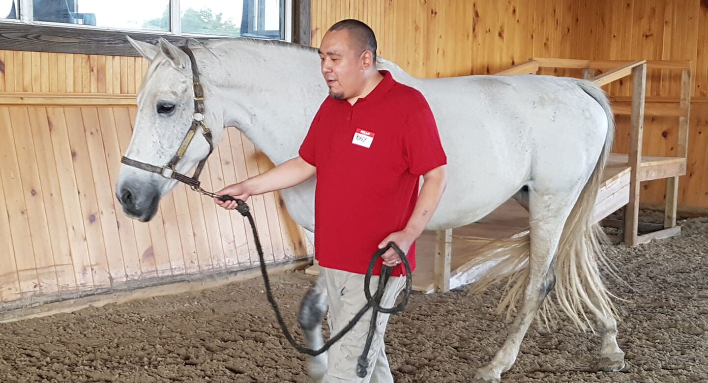Tony walks horse around indoor arena