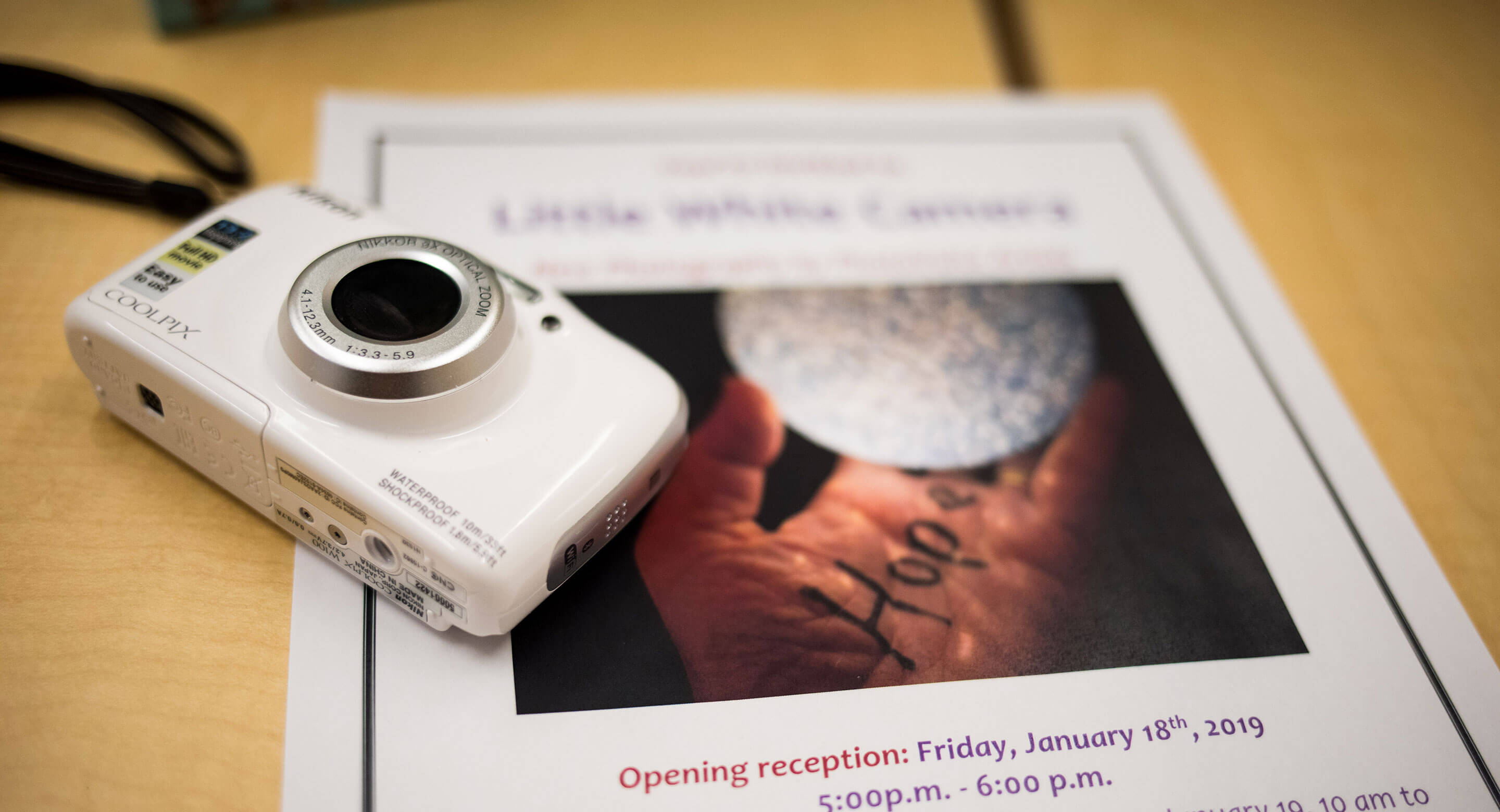 Picture of white camera beside poster for Photovoice exhibit