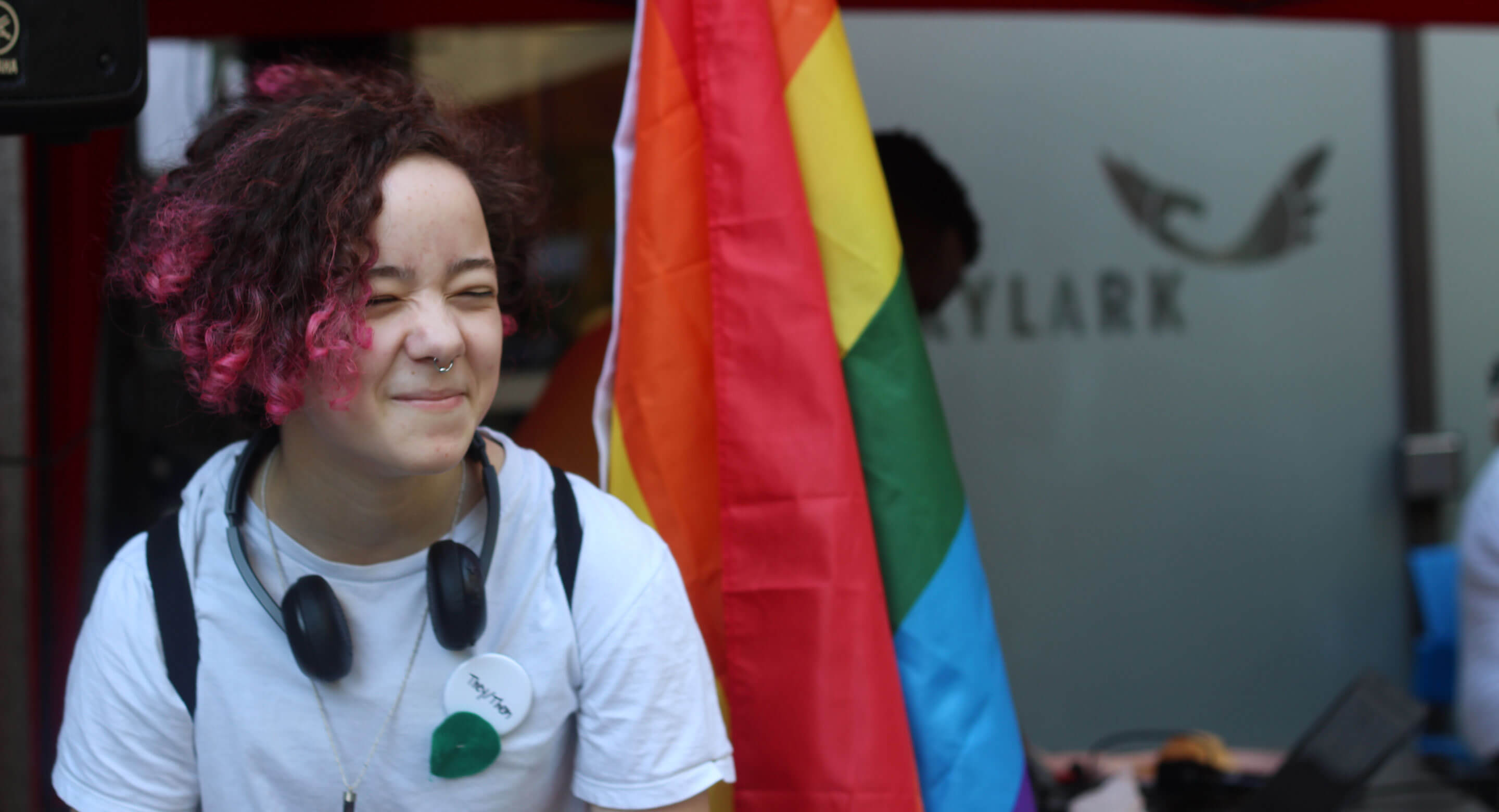 Young person in front of rainbow flag