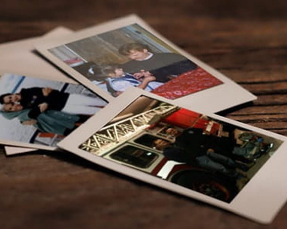 Three polaroid pictures laying on a wooden table.