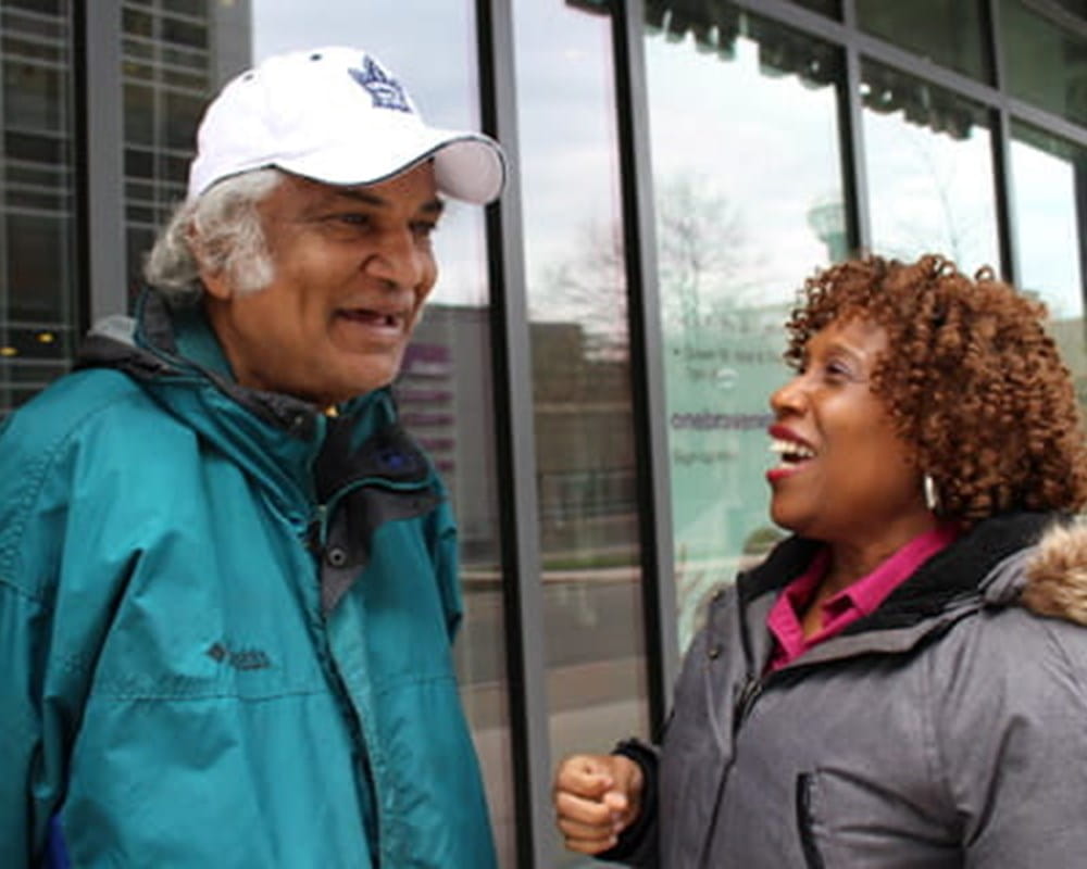 A nurse and her client, Rohan wearing winter coats and laughing outside.