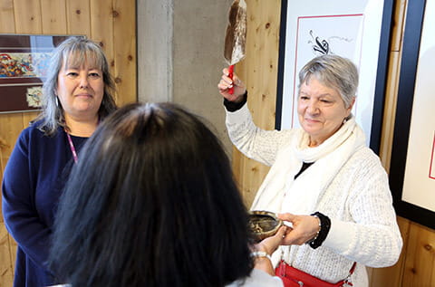 Aboriginal Service client Flo at a prayer circle smudge ceremony with social worker Barbara Hurford (holding the feather) and CAMH Elder Diane Longboat.