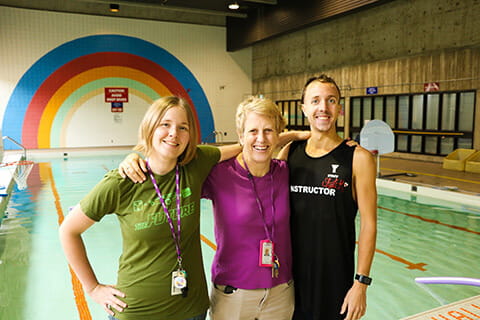 3 CAMH Lifeguards standing in front of a pool.