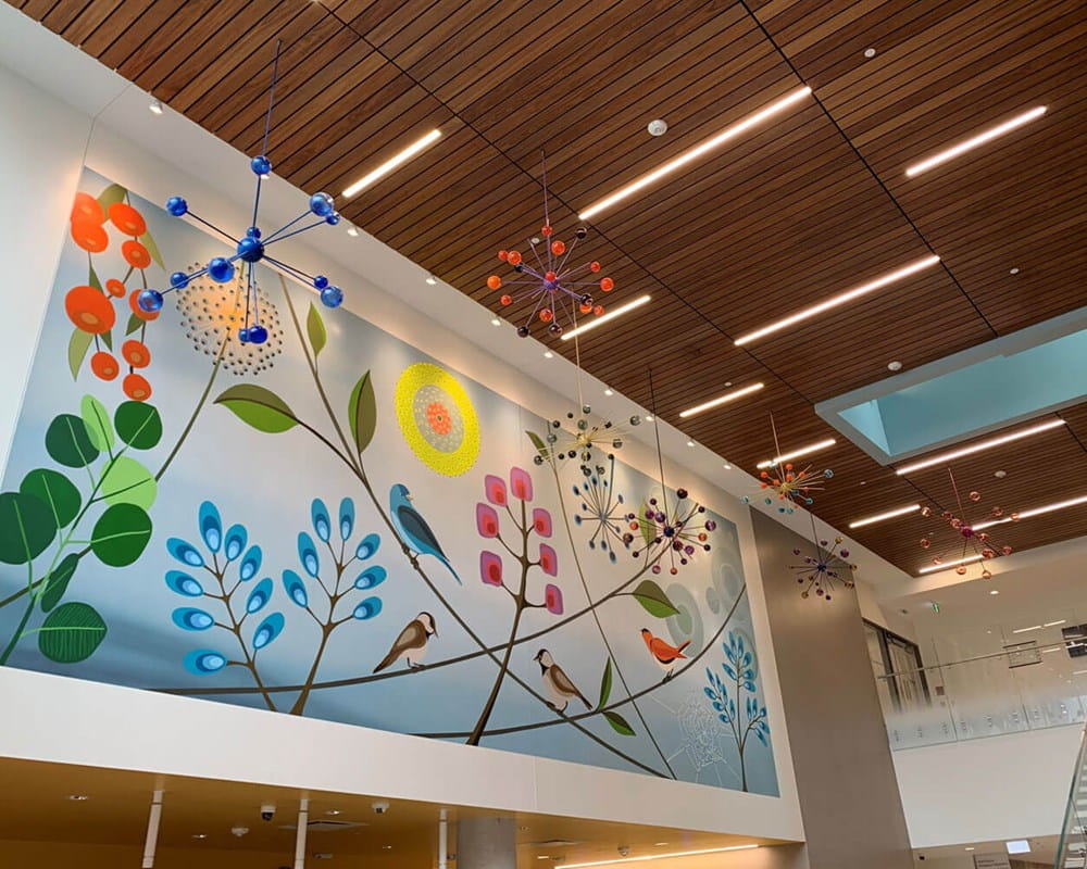 Artist: Rebecca Baird | Title: All My Relations | Location: Main lobby, Crisis & Critical Care Building | This mural and sculpture incorporates a selection of flora and fauna imagery that will portray the fluidity and dynamic interconnectedness of all nature. The series of seven glass satellite sculptures symbolically suggest a cosmic perspective. The choice to create seven satellite sculptures reflects the importance of the ‘number seven’ within Indigenous traditional teachings. The seed-like, star-like details of the sculptures create a visually descriptive bridge connecting the concept of the cosmos to the mural imagery.