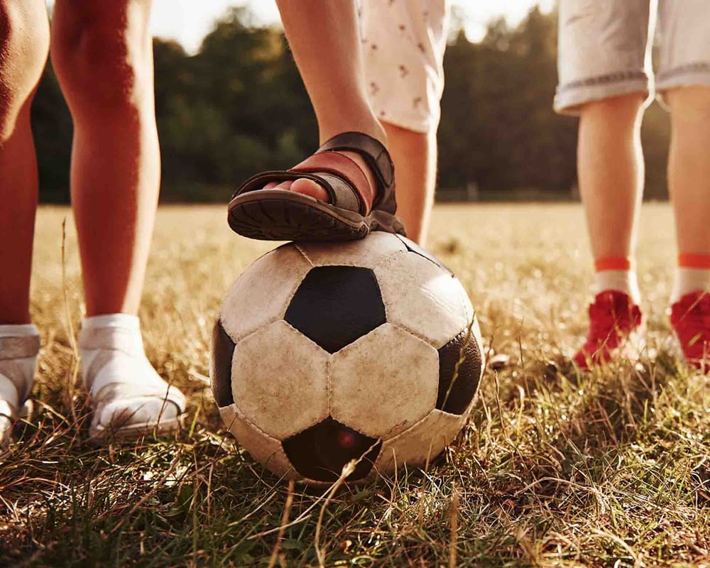 View of kids in a field on a sunny day with soccer ball.
