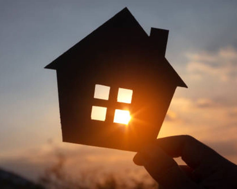 Silhouette of a house cutout, against the setting sun